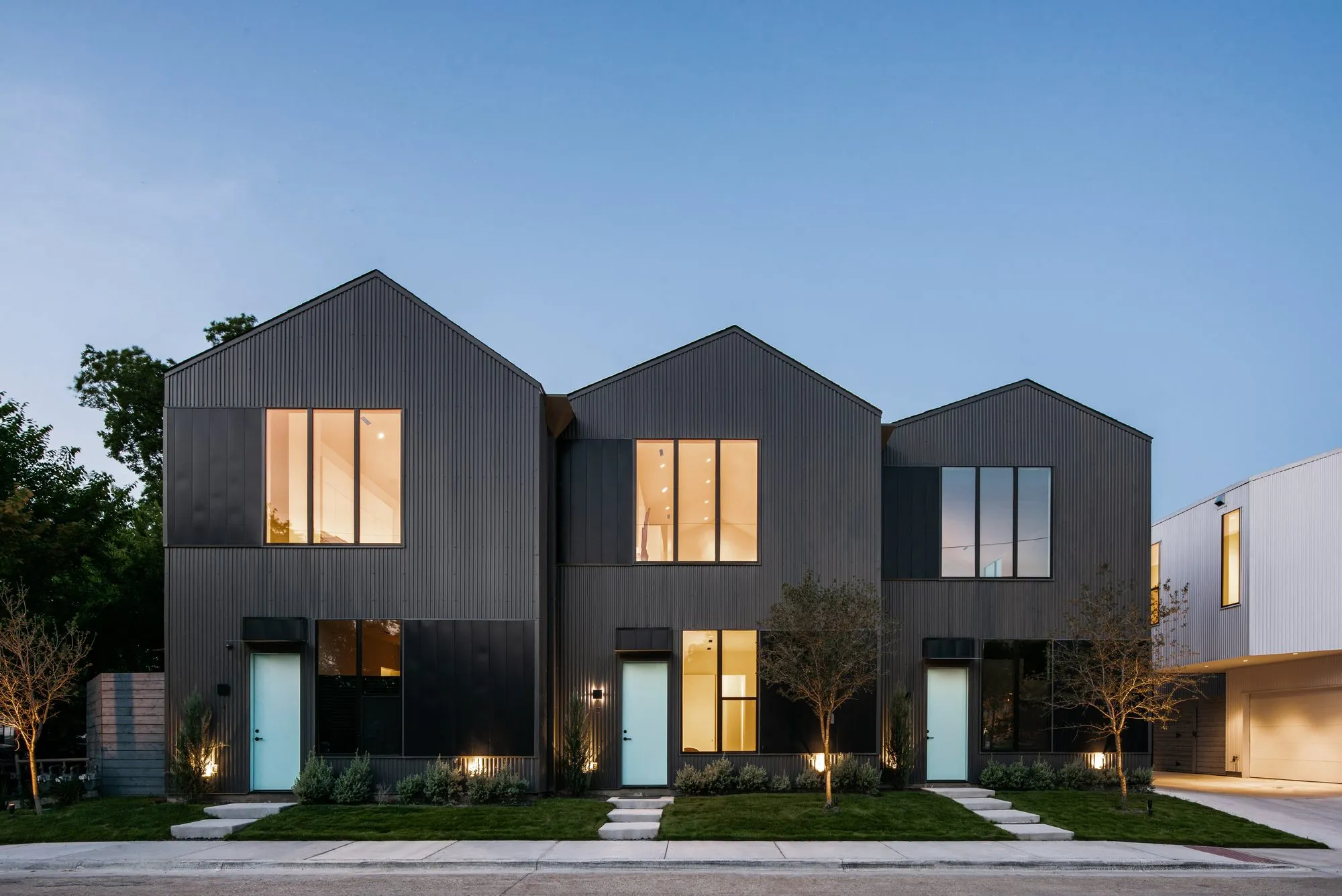 4401 Scurry Street: three dark gabled townhomes lit at dusk
