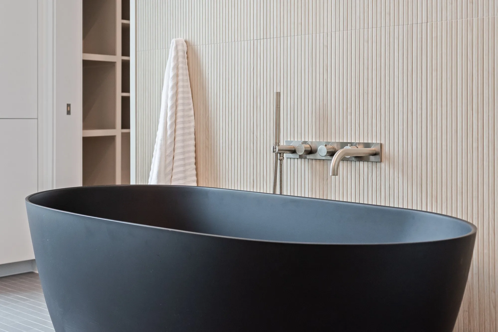 4103 Saranac: black freestanding tub against a fluted tile wall