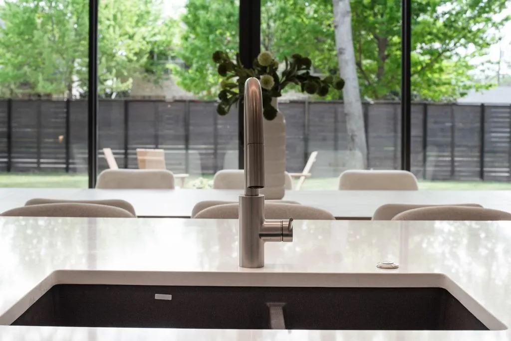 Kitchen faucet with the dining table and yard beyond