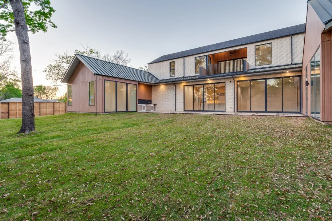 Back of the house at dusk, with glass doors opening to the lawn